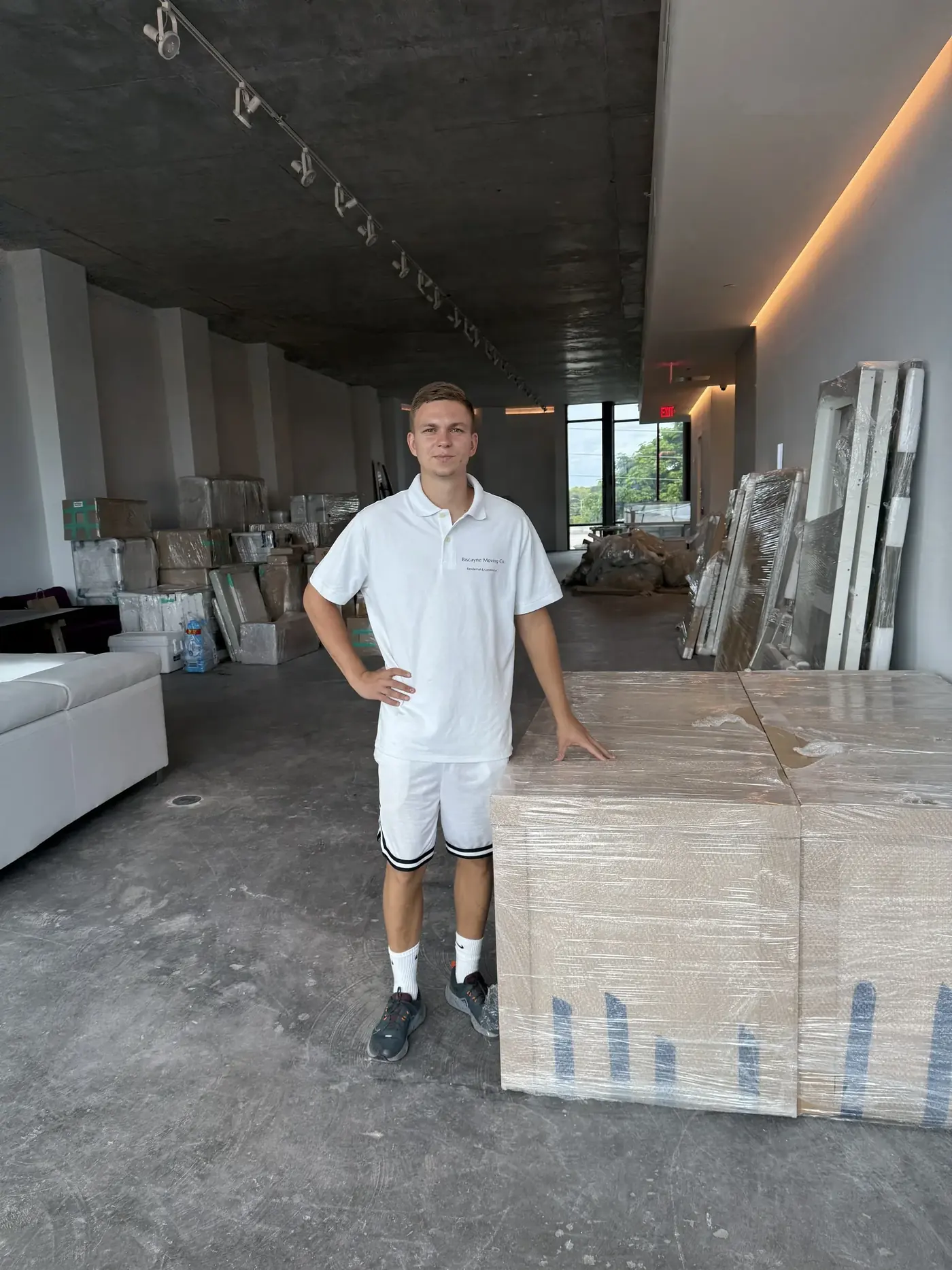 Biscayne Moving Co. crew member beside wrapped furniture during a Miami commercial move